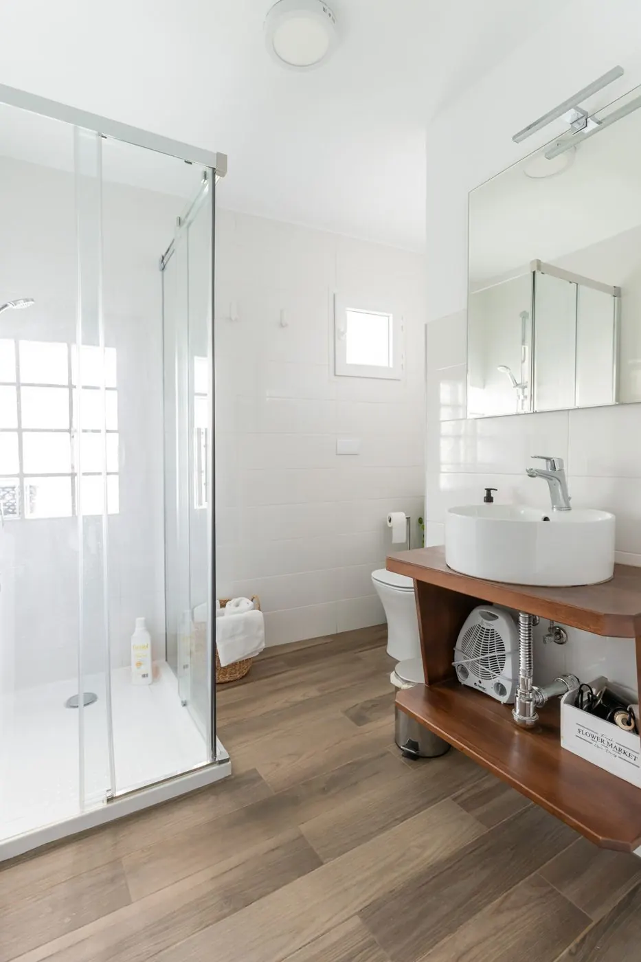 Baño con ducha de cristal y lavabo de madera