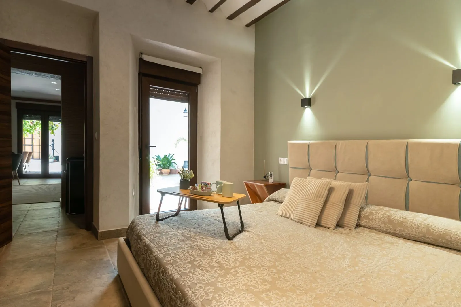 Dormitorio de la Morada del Conde con vigas de madera, cabecero tapizado y cama de 180